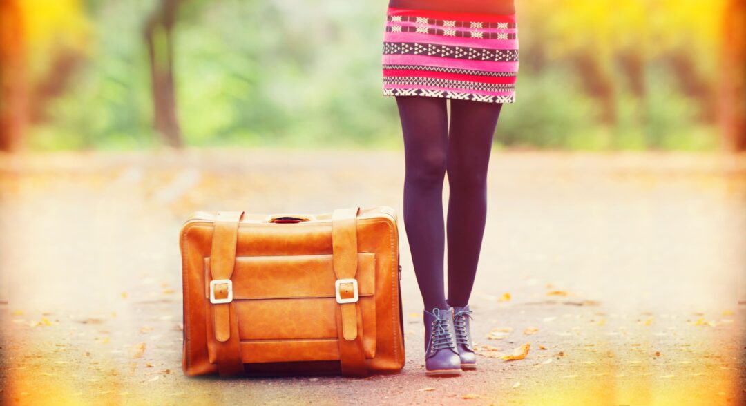 Eine Frau, die Kompressionsstrümpfe trägt, steht neben einer Reisetasche