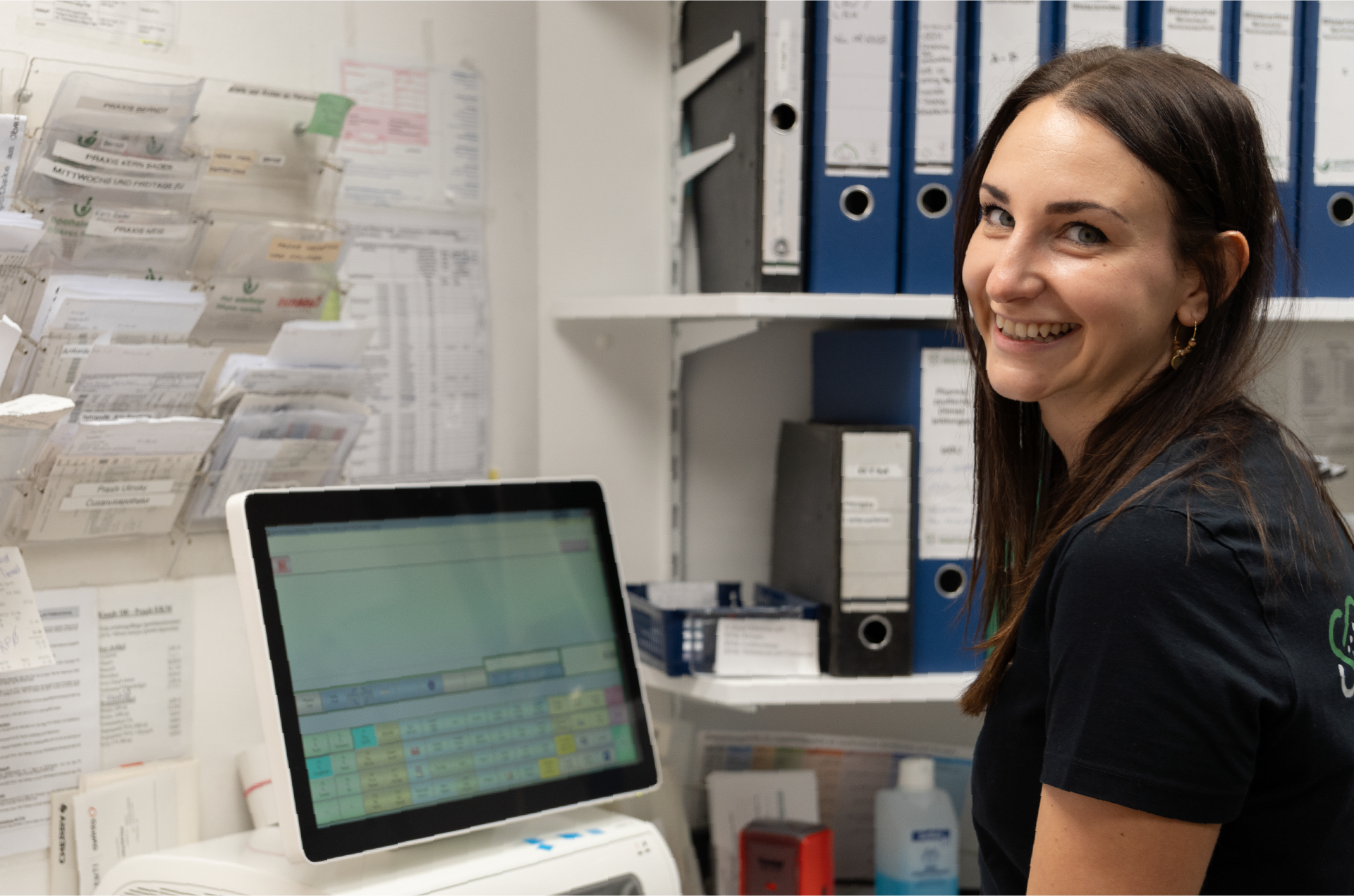 Mitarbeiterin, die an einem Computer steht, lächelt in die Kamera