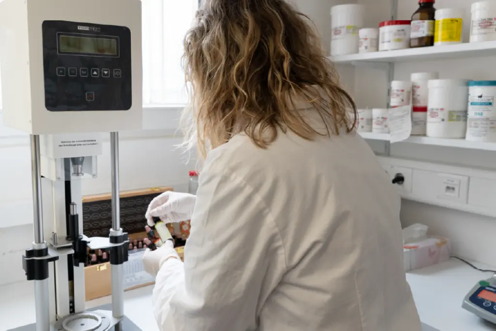 Labormitarbeiterin, die gerade ein Gefäß aus einer Holzbox entnimmt