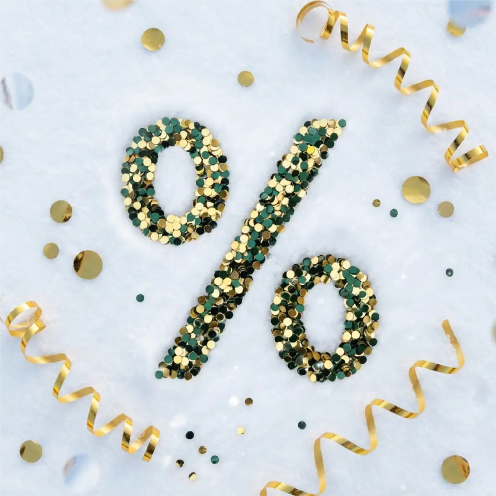 Goldene und Grüne Konfettiteilchen liegen im Schnee und formen dabei ein Prozentzeichen